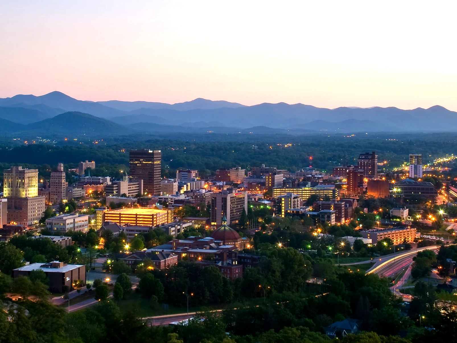 Aerial view of Asheville, North Carolina at dusk with mountains in the background. Local SEO helps Asheville small businesses improve search visibility and reach more customers in the area.